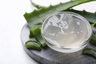 Aloe vera gel and slices of plant on white background, closeup. Space for text