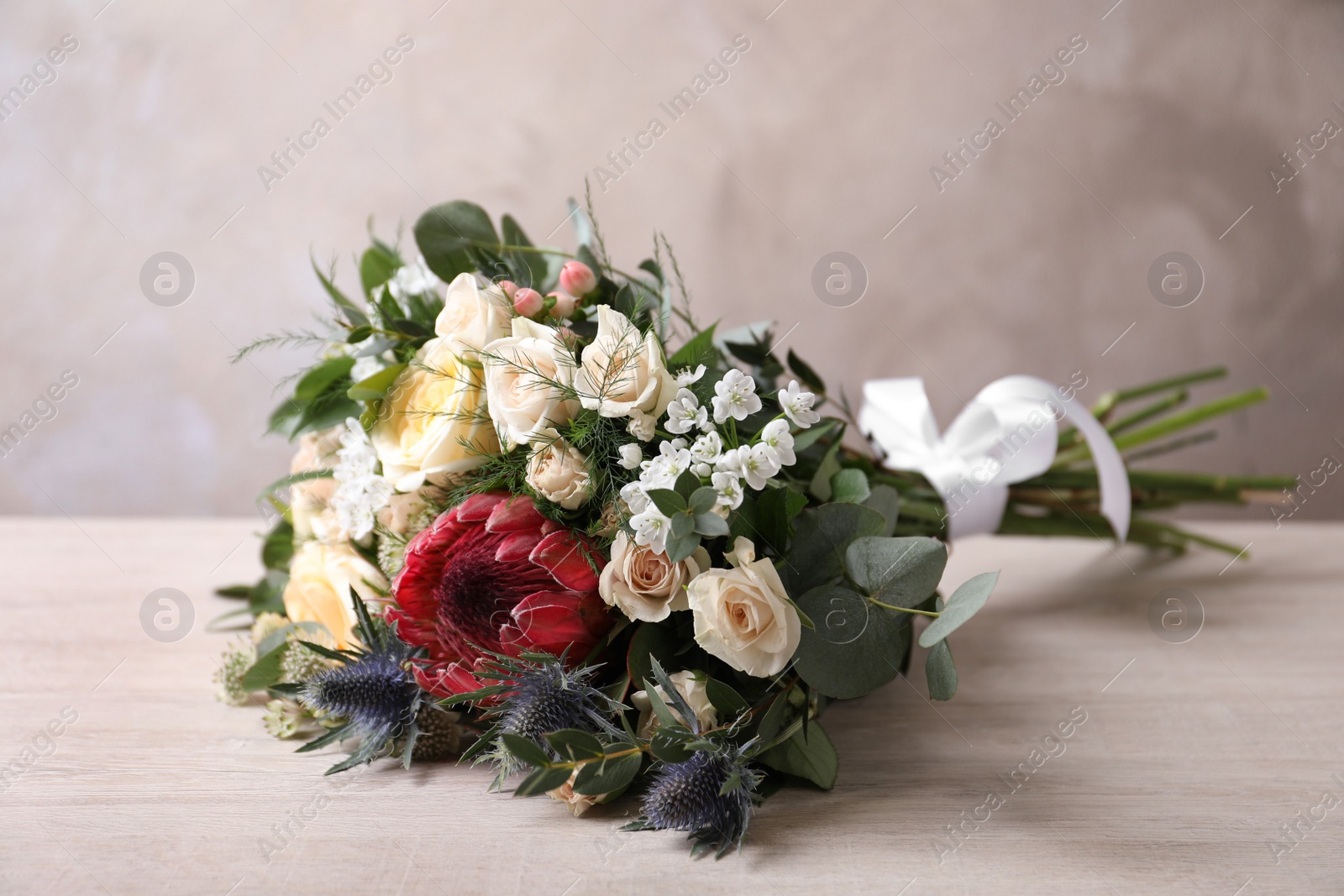 Photo of Beautiful bouquet with roses on white wooden table
