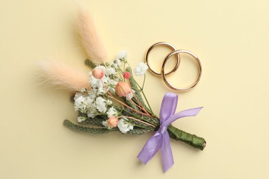 Photo of Small stylish boutonniere and rings on beige background, flat lay