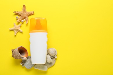 Bottle of suntan cream and seashells on yellow background, flat lay. Space for text