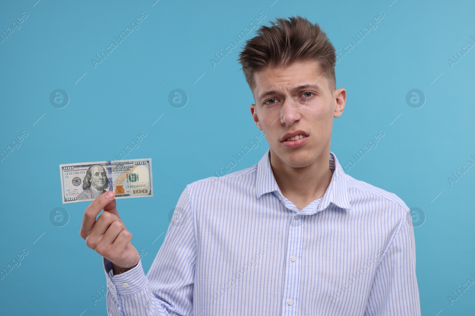 Photo of Upset man with dollar banknote on light blue background