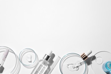Photo of Flat lay composition with petri dishes and samples of cosmetic serums on white background. Space for text