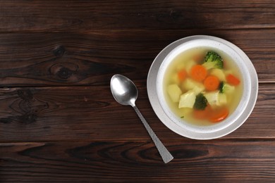 Tasty chicken soup with vegetables in bowl served on wooden table, top view. Space for text