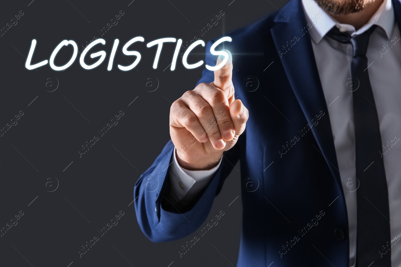 Image of Businessman pointing at word LOGISTICS on virtual screen against dark background, closeup 