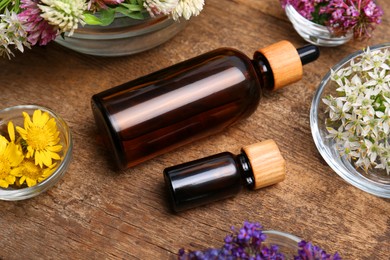 Bottles of essential oils and beautiful flowers on wooden table