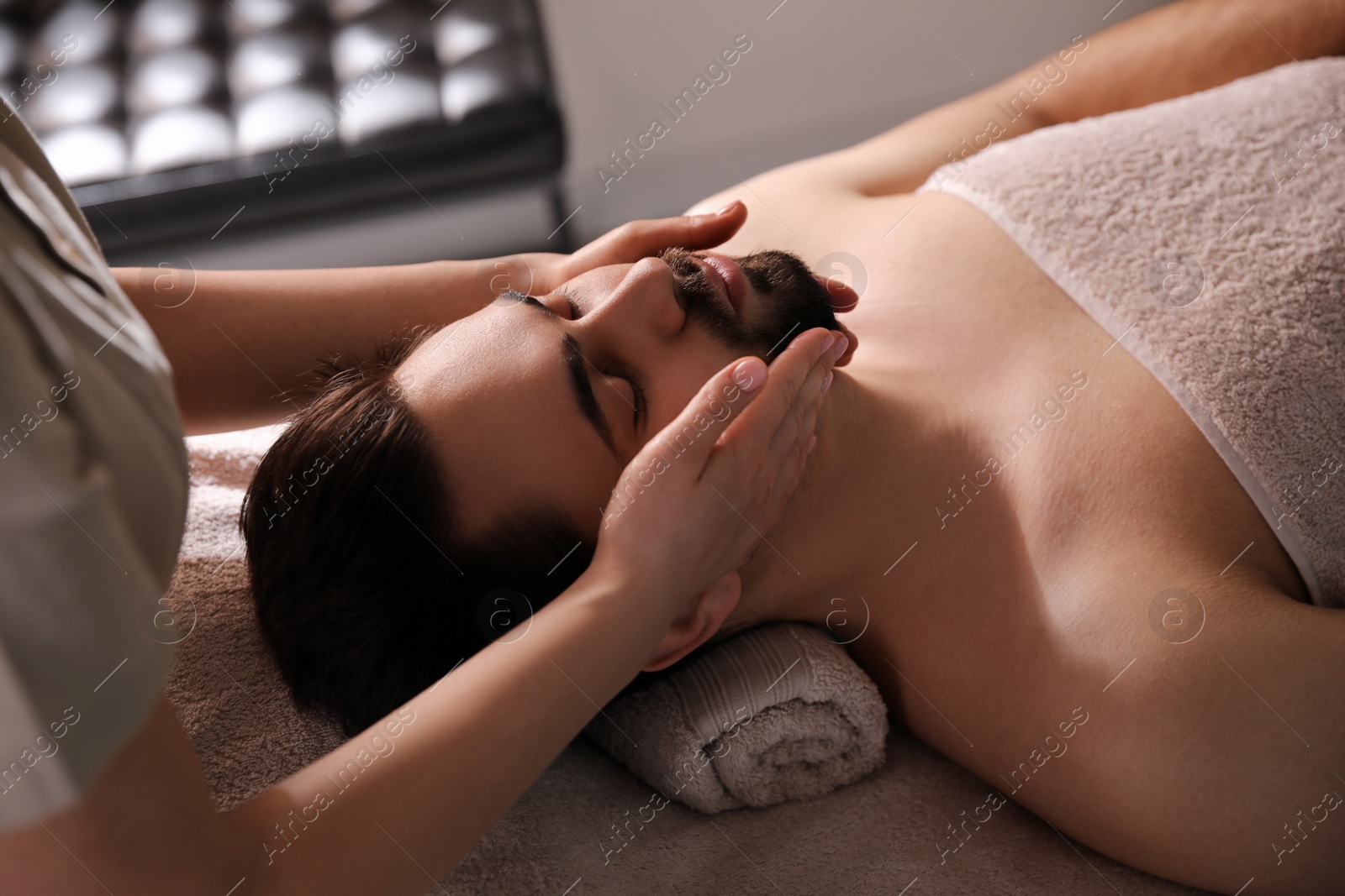 Photo of Young man receiving facial massage in beauty salon