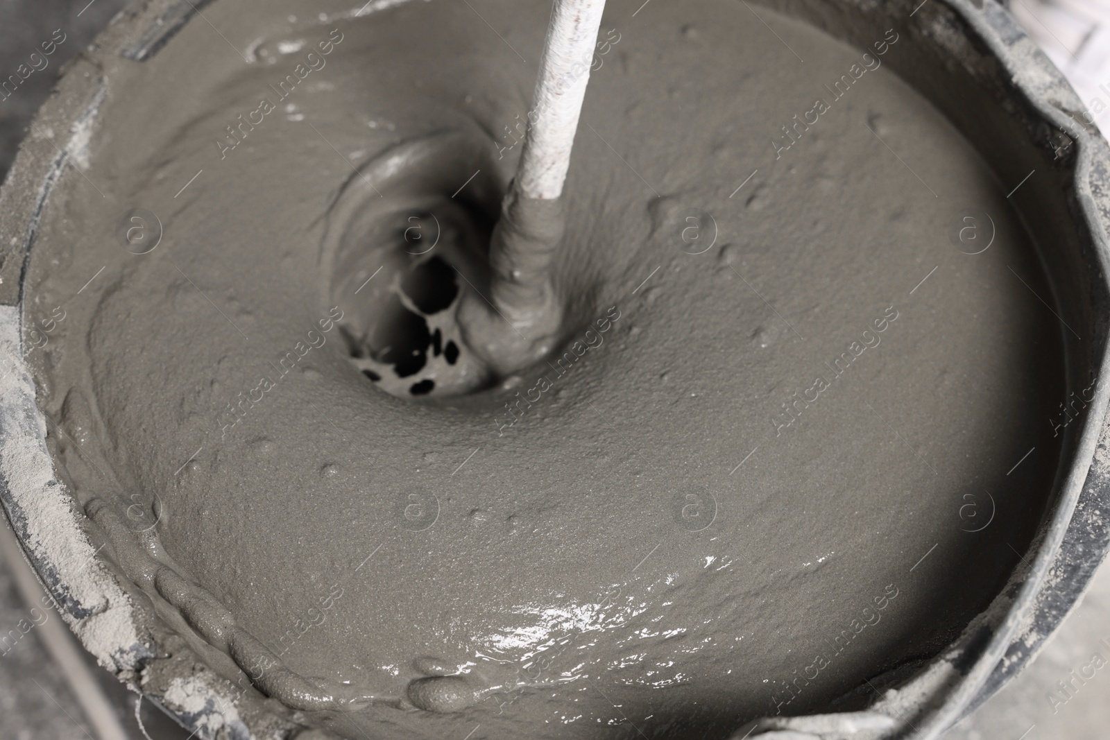 Photo of Mixing concrete in bucket indoors, closeup view