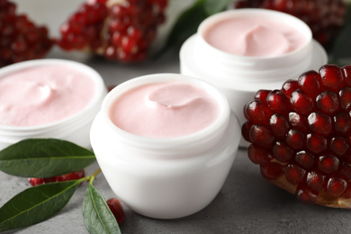 Natural facial mask, pomegranate seeds and green leaves on light grey table, closeup