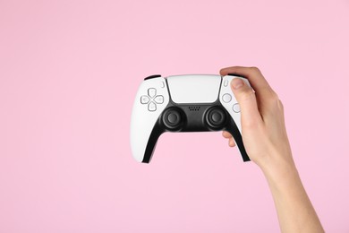 Woman with game controller on pink background, closeup