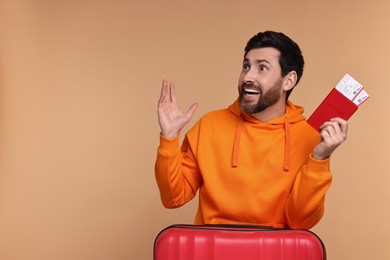 Happy man with passport, suitcase and tickets on beige background. Space for text