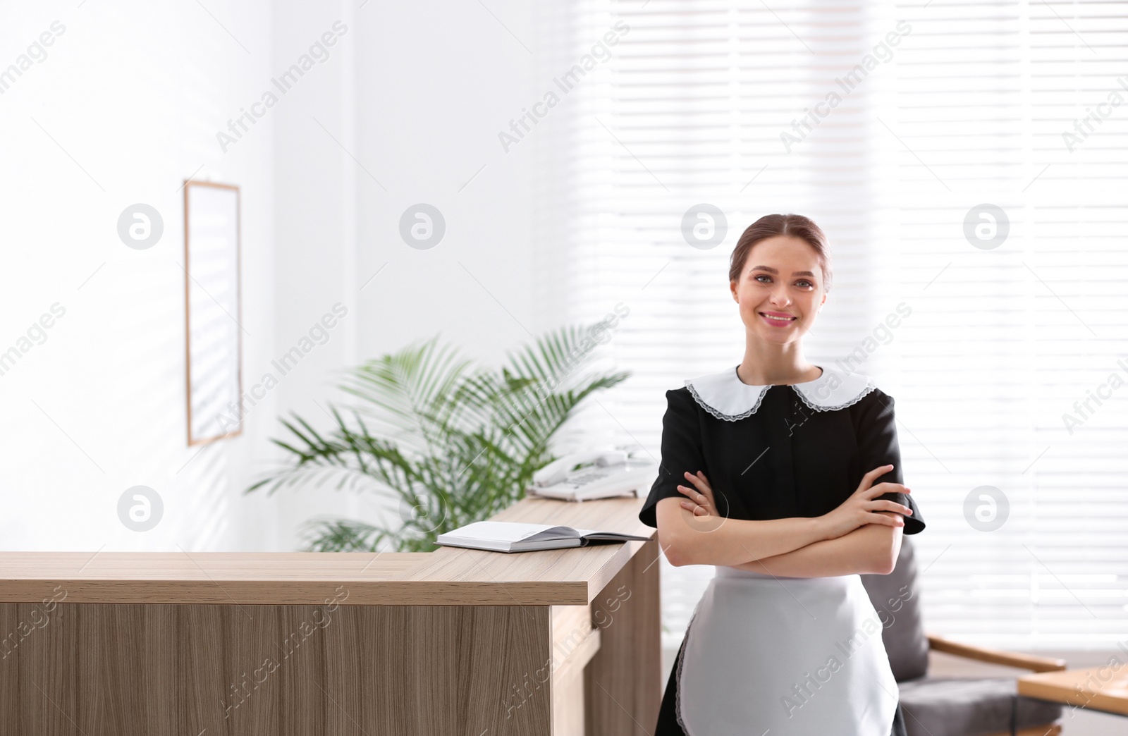 Photo of Young chambermaid near reception in hotel. Space for text