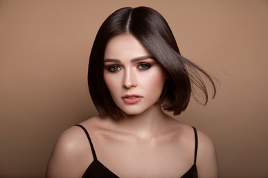 Portrait of pretty young woman with short hair on pastel brown background