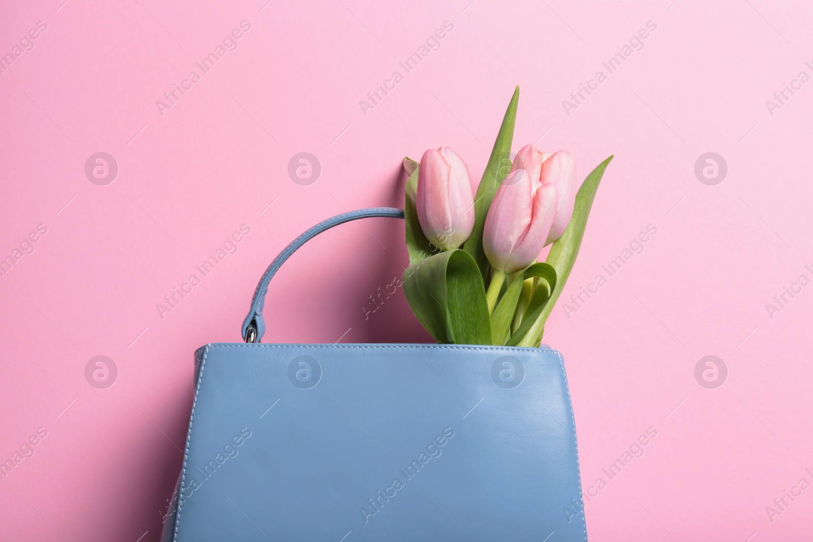 Photo of Flat lay composition with stylish woman's handbag and spring flowers on color background