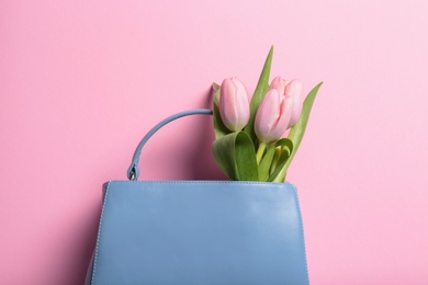 Photo of Flat lay composition with stylish woman's handbag and spring flowers on color background