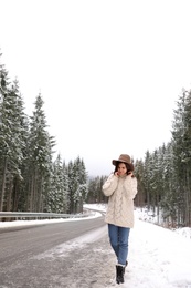 Young woman walking near snowy forest. Winter vacation