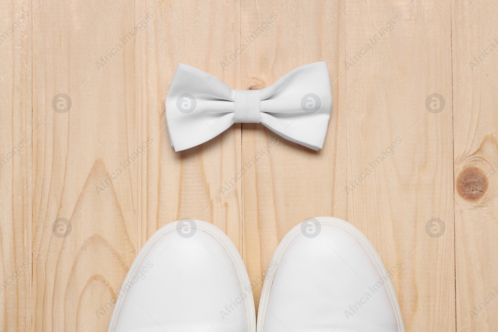 Photo of Stylish white bow tie and shoes on wooden background, flat lay