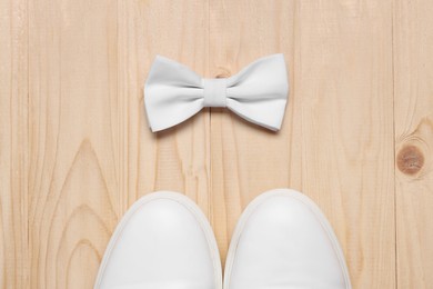 Photo of Stylish white bow tie and shoes on wooden background, flat lay