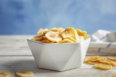 Photo of Bowl with sweet banana slices on wooden  table. Dried fruit as healthy snack
