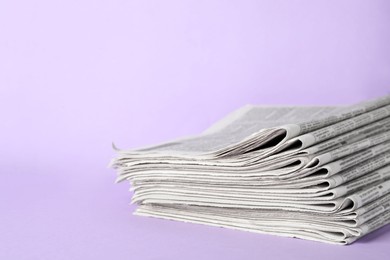 Photo of Stack of newspapers on light violet background. Journalist's work