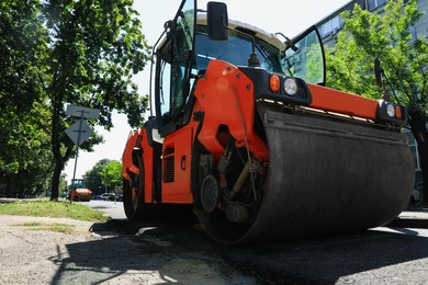 Photo of Roller working on city street, low angle view. Road repairing