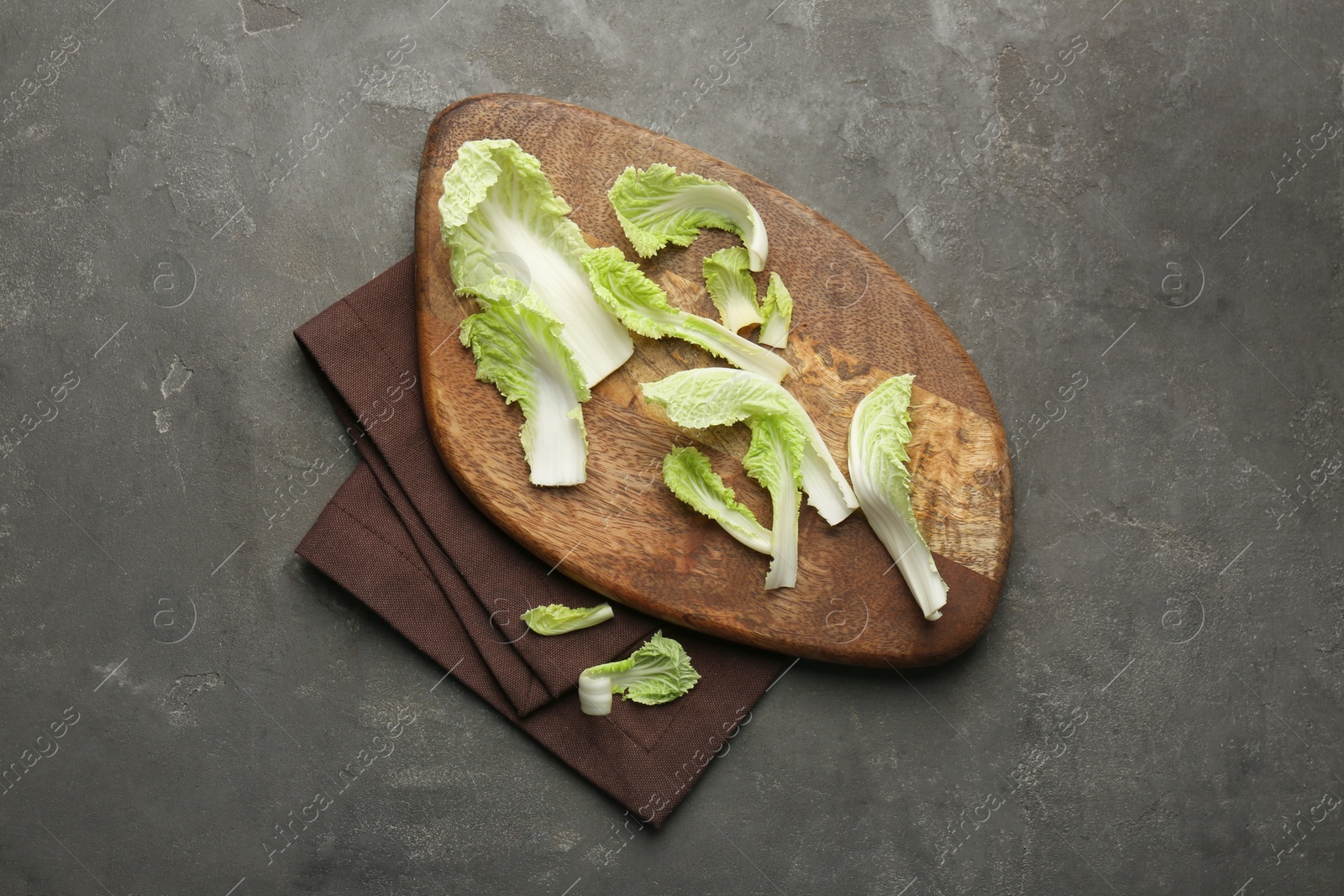 Photo of Pieces of fresh Chinese cabbage on gray textured table, top view