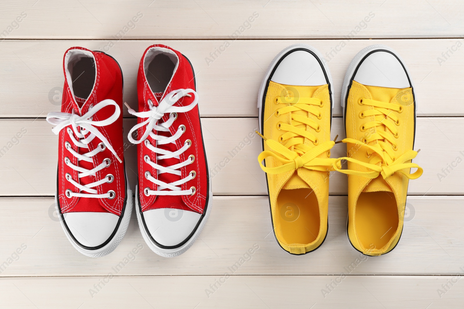 Photo of Different stylish sneakers on white wooden table, flat lay