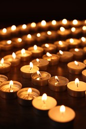 Burning candles on wooden table in darkness