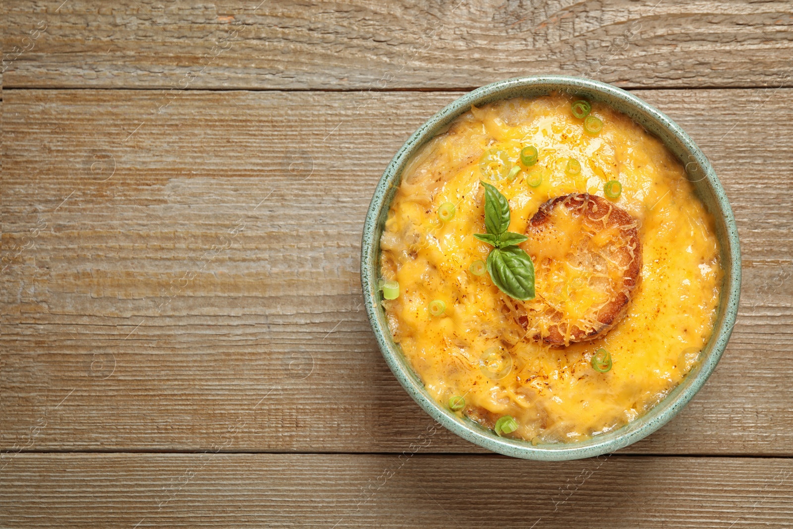 Photo of Tasty homemade French onion soup on wooden table, top view. Space for text