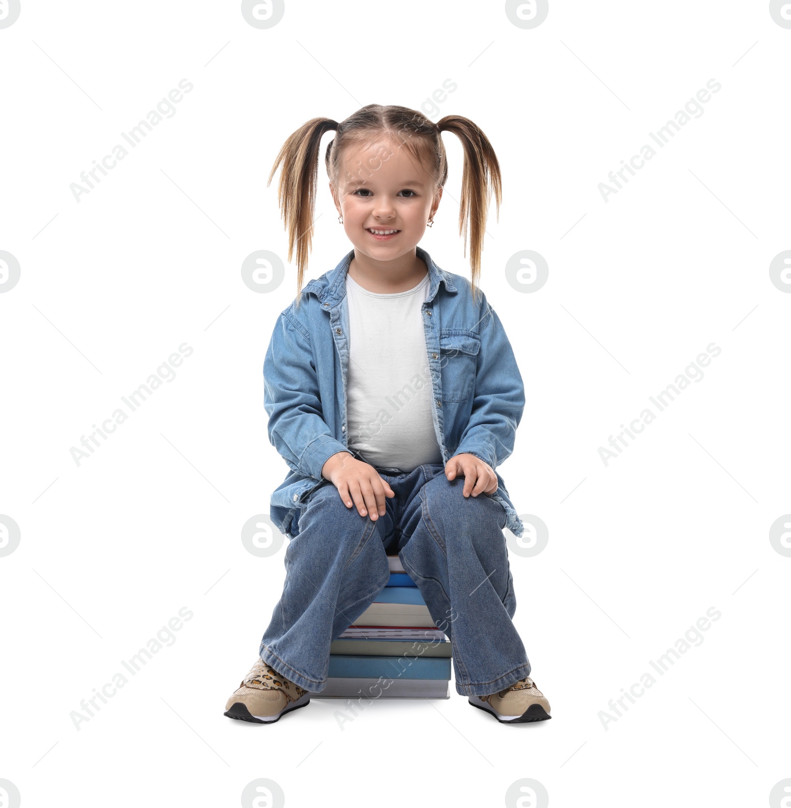 Photo of Cute little girl sitting on stack of books against white background