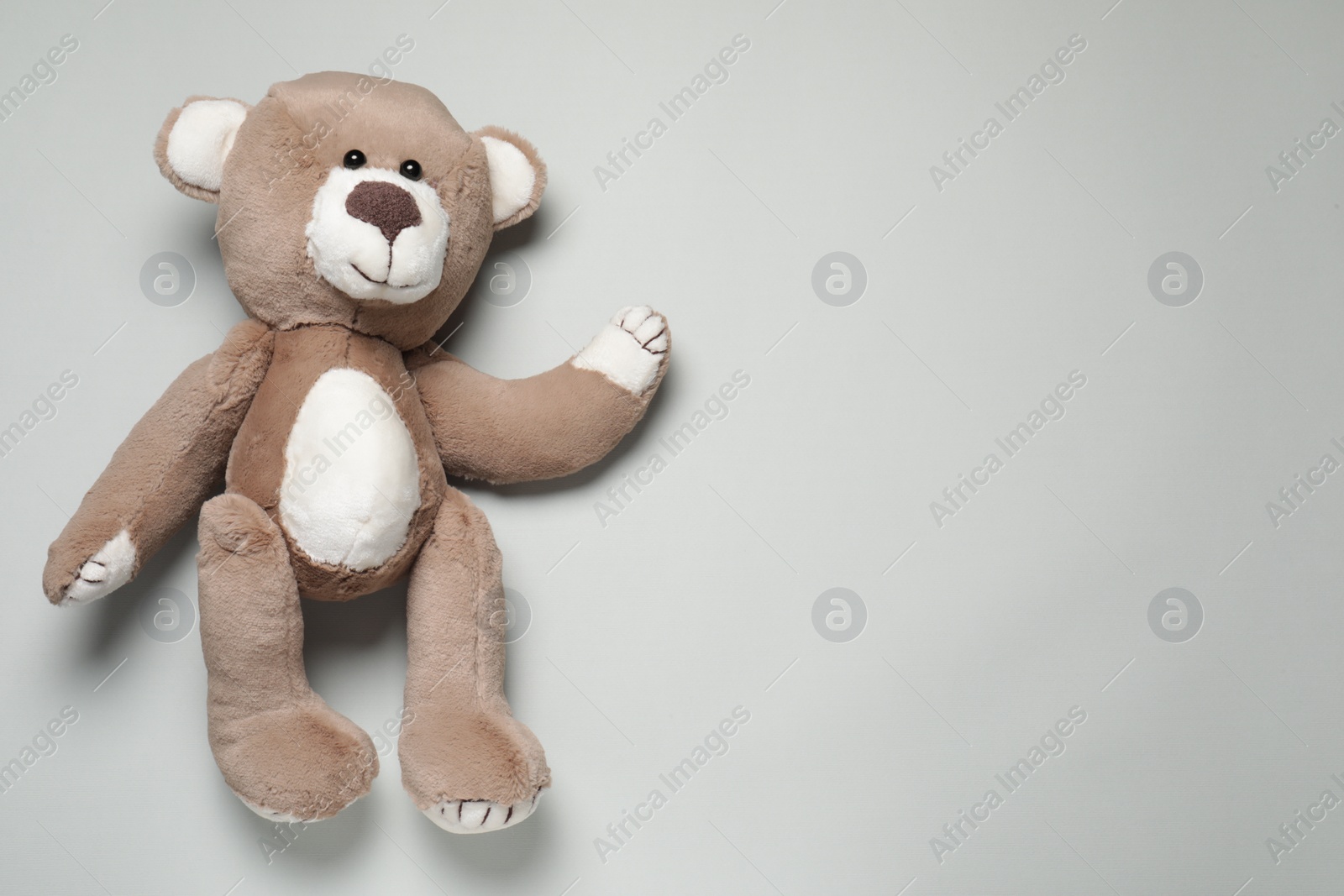Photo of Cute teddy bear on light grey background, top view. Space for text