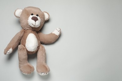 Cute teddy bear on light grey background, top view. Space for text