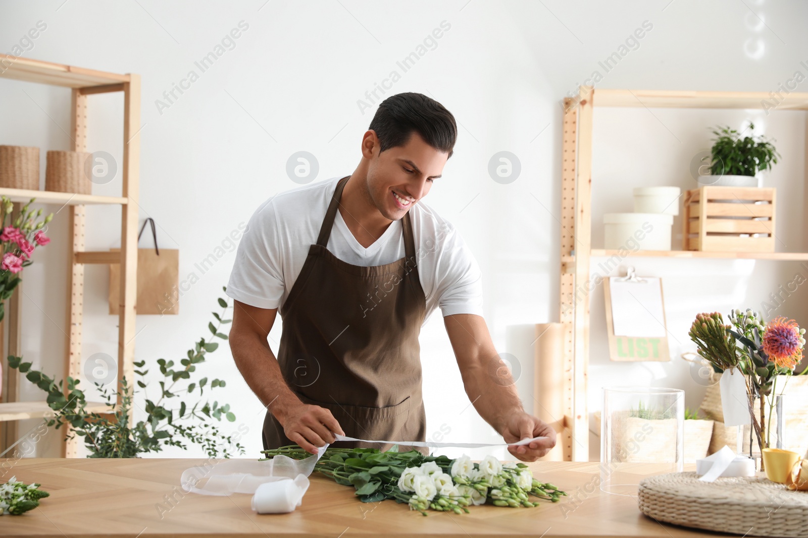 Photo of Florist making beautiful bouquet at table in workshop