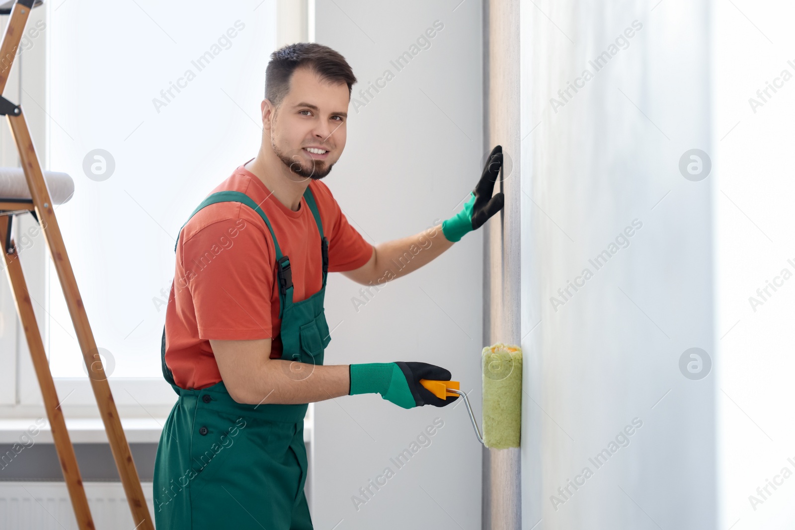 Photo of Man hanging stylish gray wallpaper in room