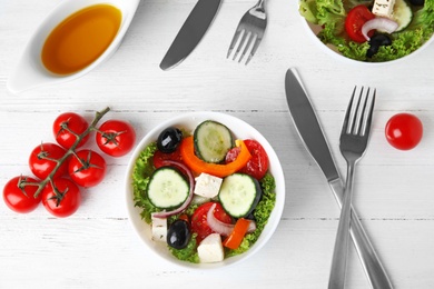 Photo of Tasty fresh Greek salad on white wooden table, flat lay