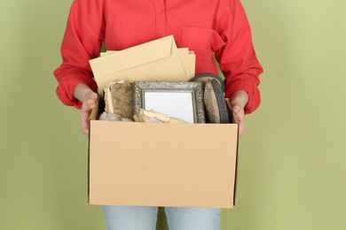 Photo of Woman holding box of unwanted stuff on green background, closeup