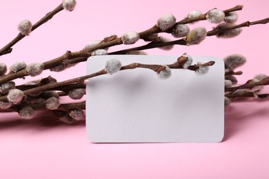 Photo of Beautiful blooming willow branches and blank paper card on pink background. Space for text