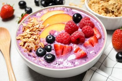 Photo of Delicious acai smoothie with fruits and oatmeal in bowl on table, closeup