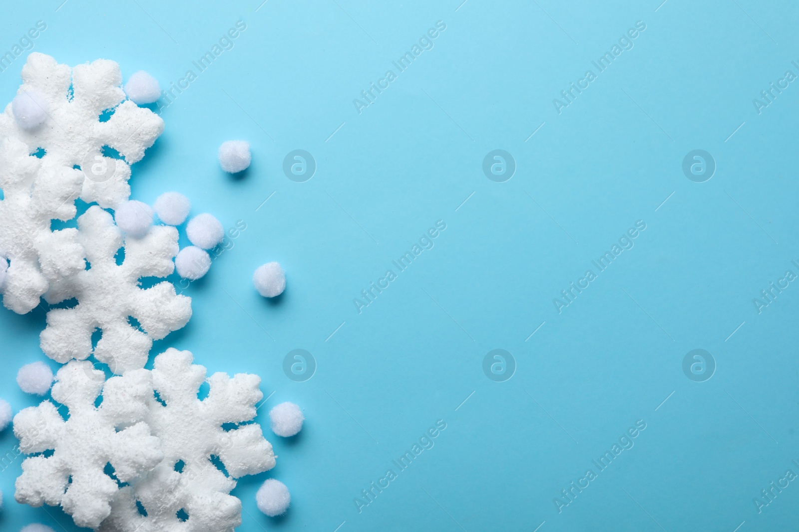 Photo of Beautiful snowflakes and decorative balls on light blue background, flat lay. Space for text