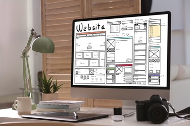 Image of Computer with sketch of website planning and design on white table