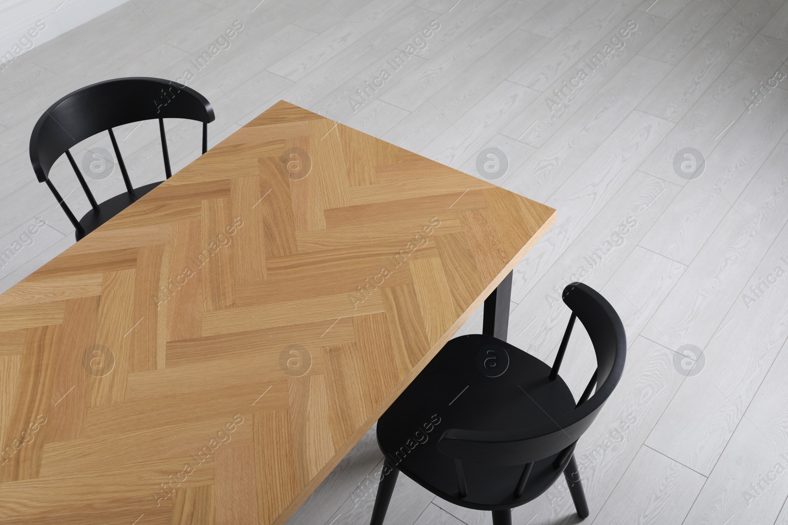 Photo of Wooden table and black chairs indoors, above view. Interior design