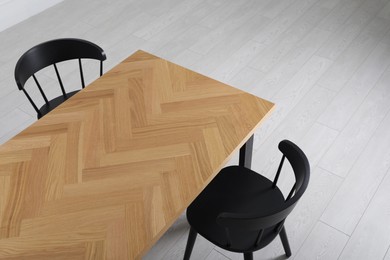 Photo of Wooden table and black chairs indoors, above view. Interior design