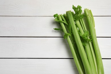 Photo of Fresh celery stalks on white wooden table, top view. Space for text