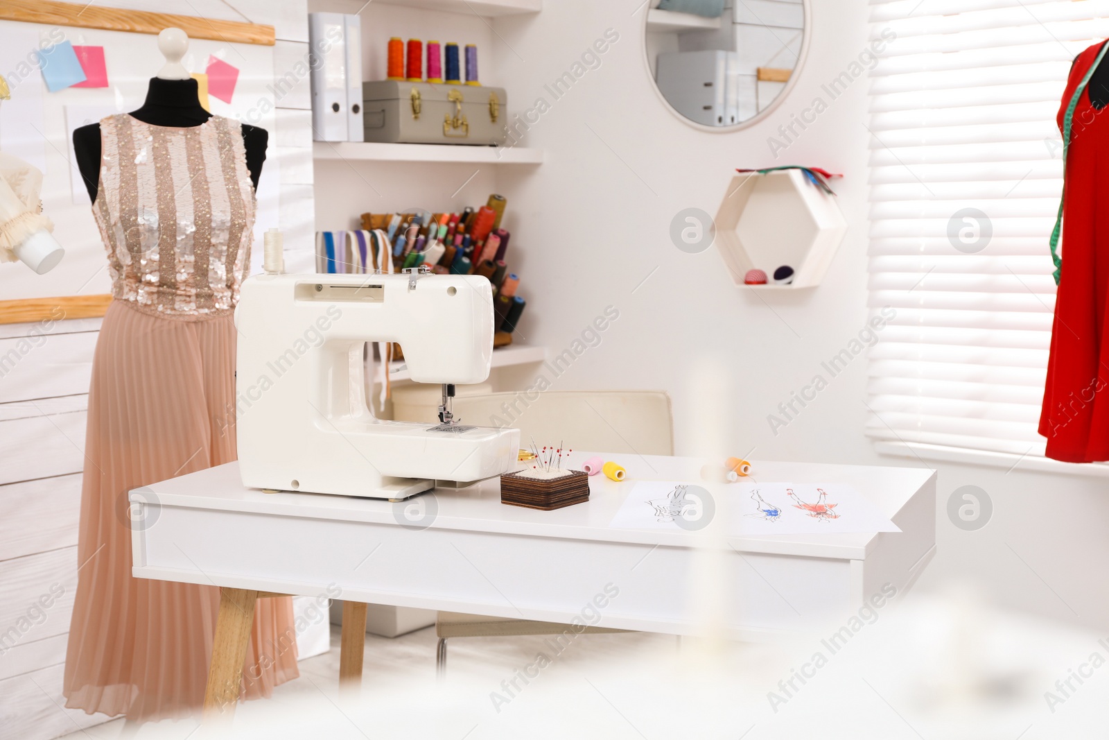 Photo of Dressmaking workshop interior with modern sewing machine, mannequin and accessories