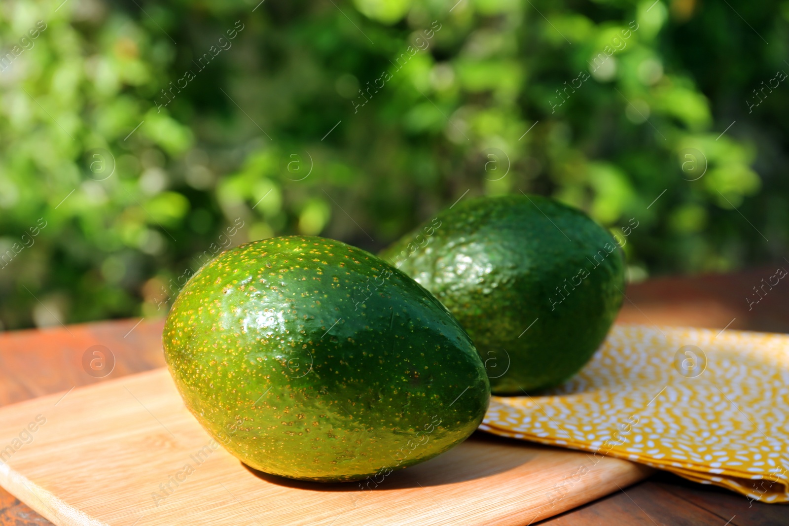 Photo of Fresh ripe avocados on wooden table outdoors