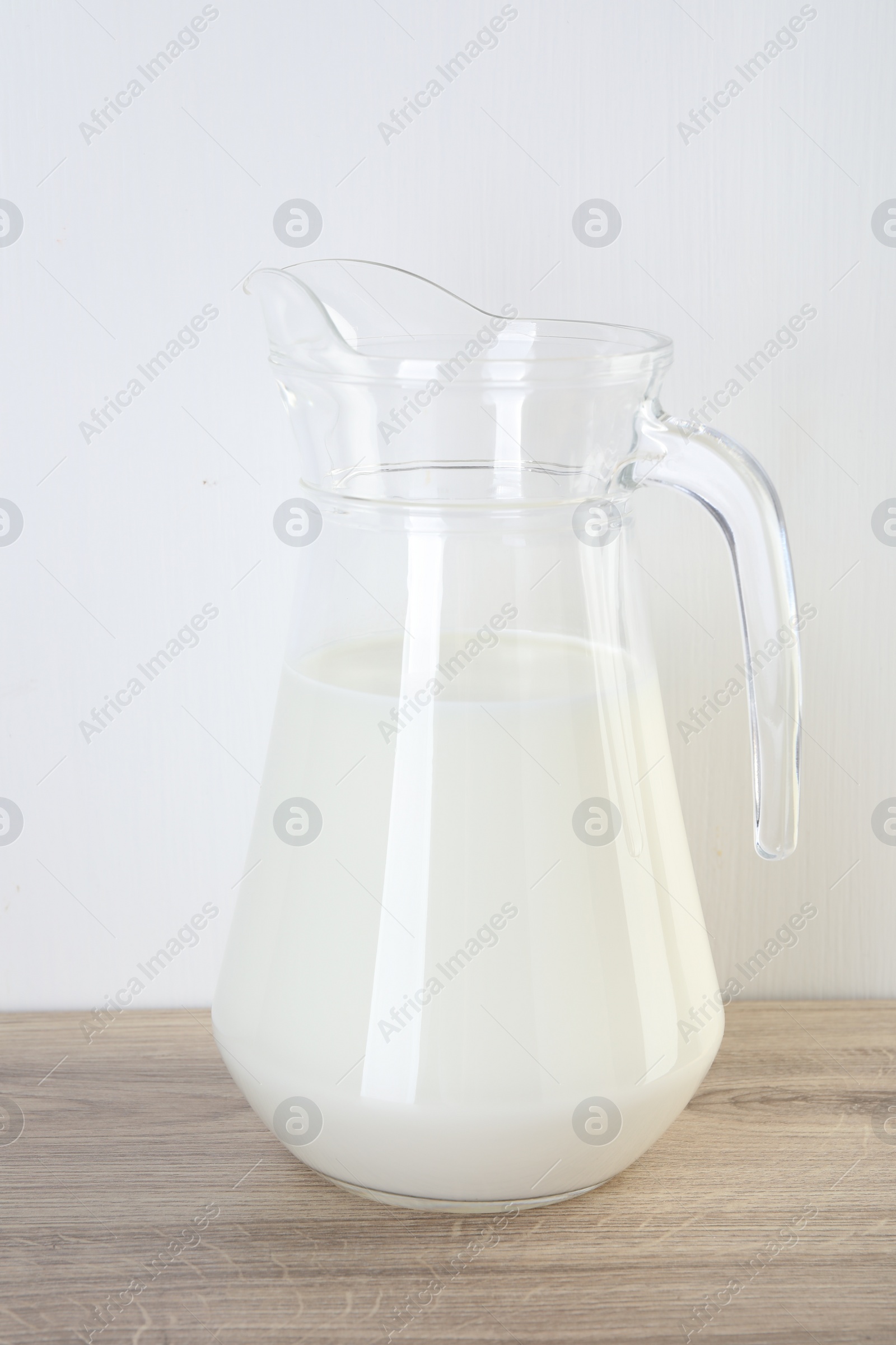 Photo of Jug of fresh milk on wooden table