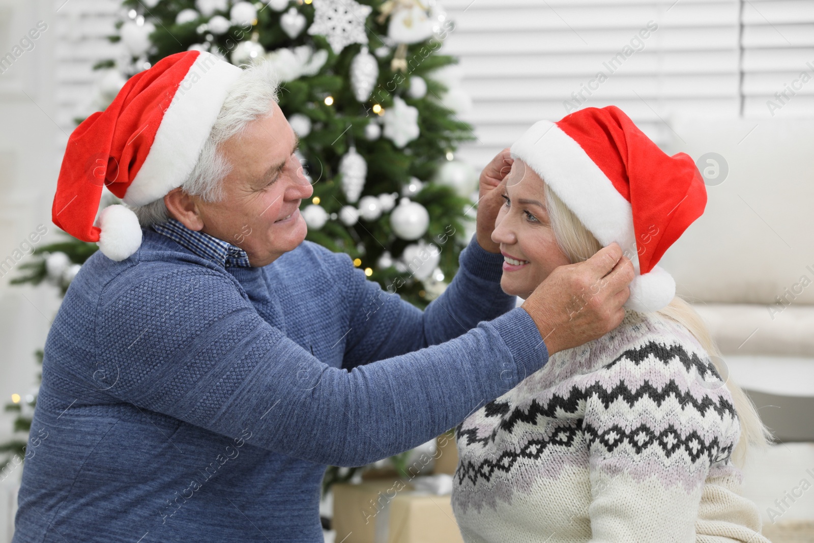 Photo of Happy mature couple in Santa hats at home. Christmas celebration