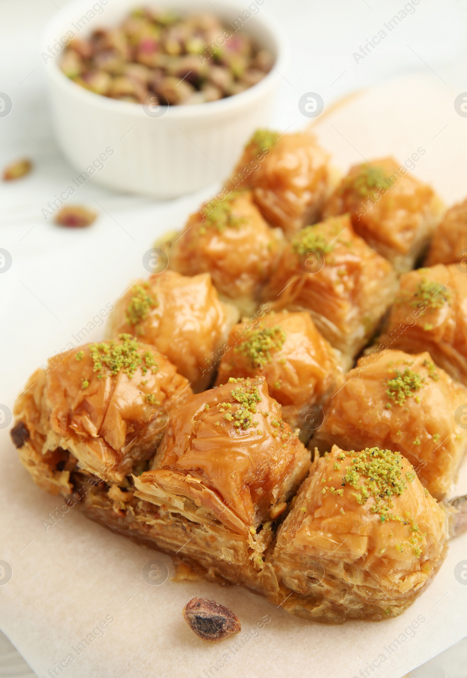 Photo of Delicious sweet baklava with pistachios on parchment paper, closeup