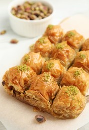 Photo of Delicious sweet baklava with pistachios on parchment paper, closeup