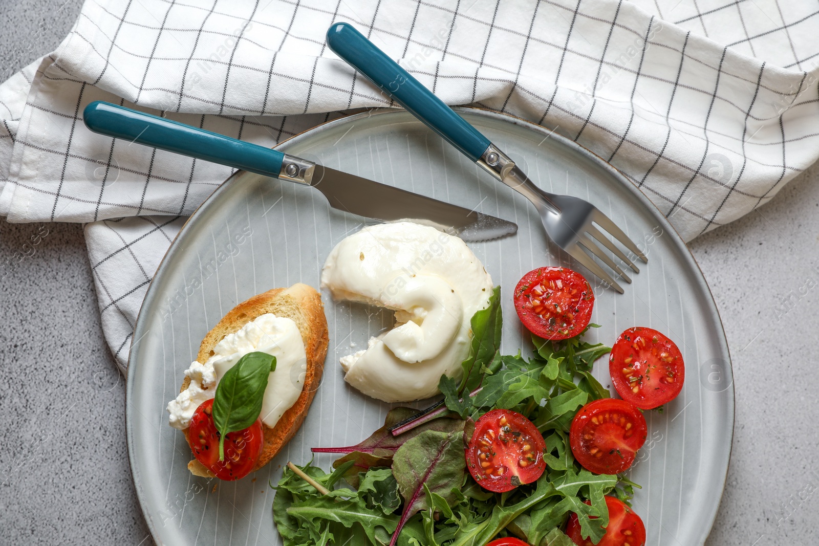 Photo of Delicious burrata cheese with tomatoes, arugula and toast served on grey table, top view