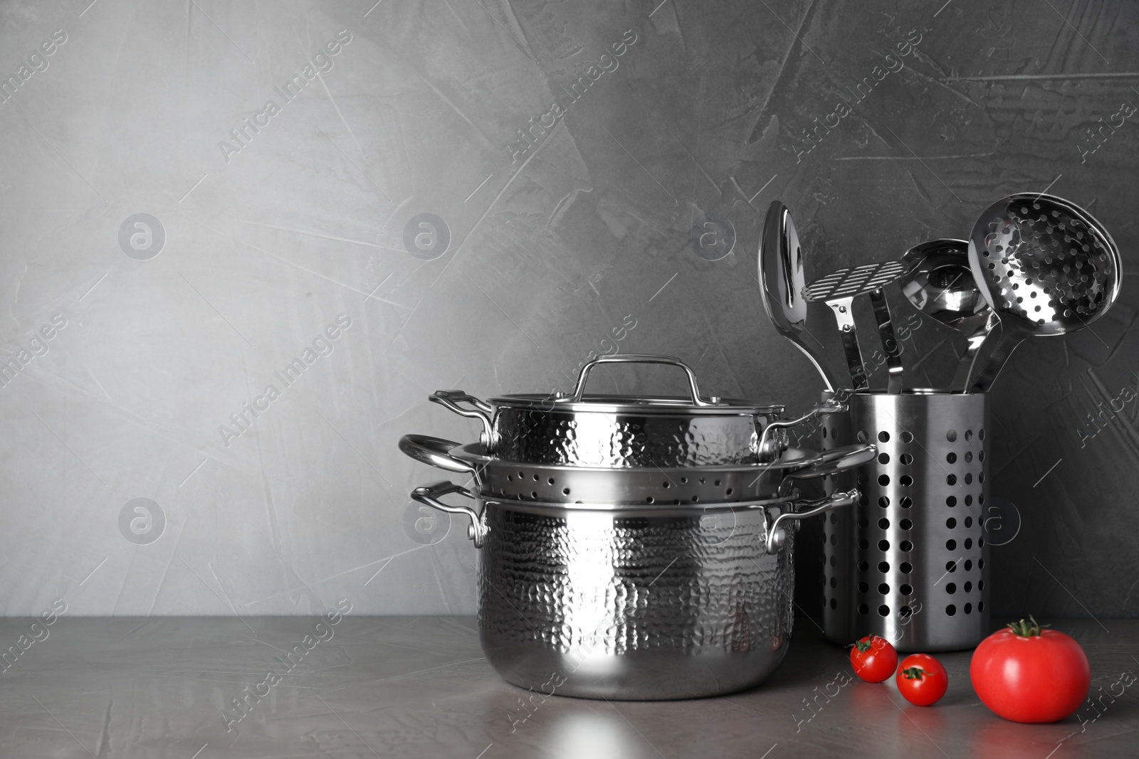 Photo of Set of clean cookware and utensils on table against grey background. Space for text